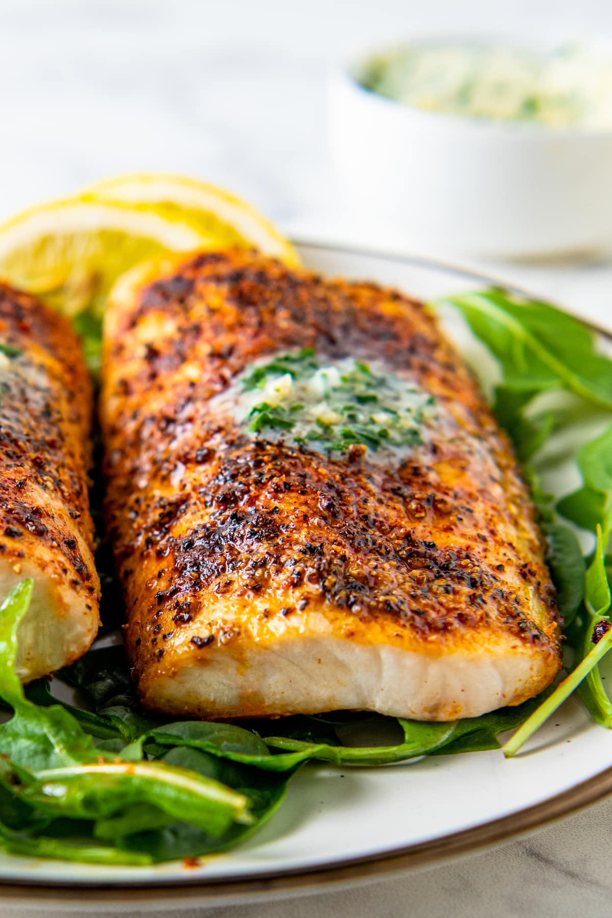 Garlic herb butter is melting on top of a fully cooked fish filet. 