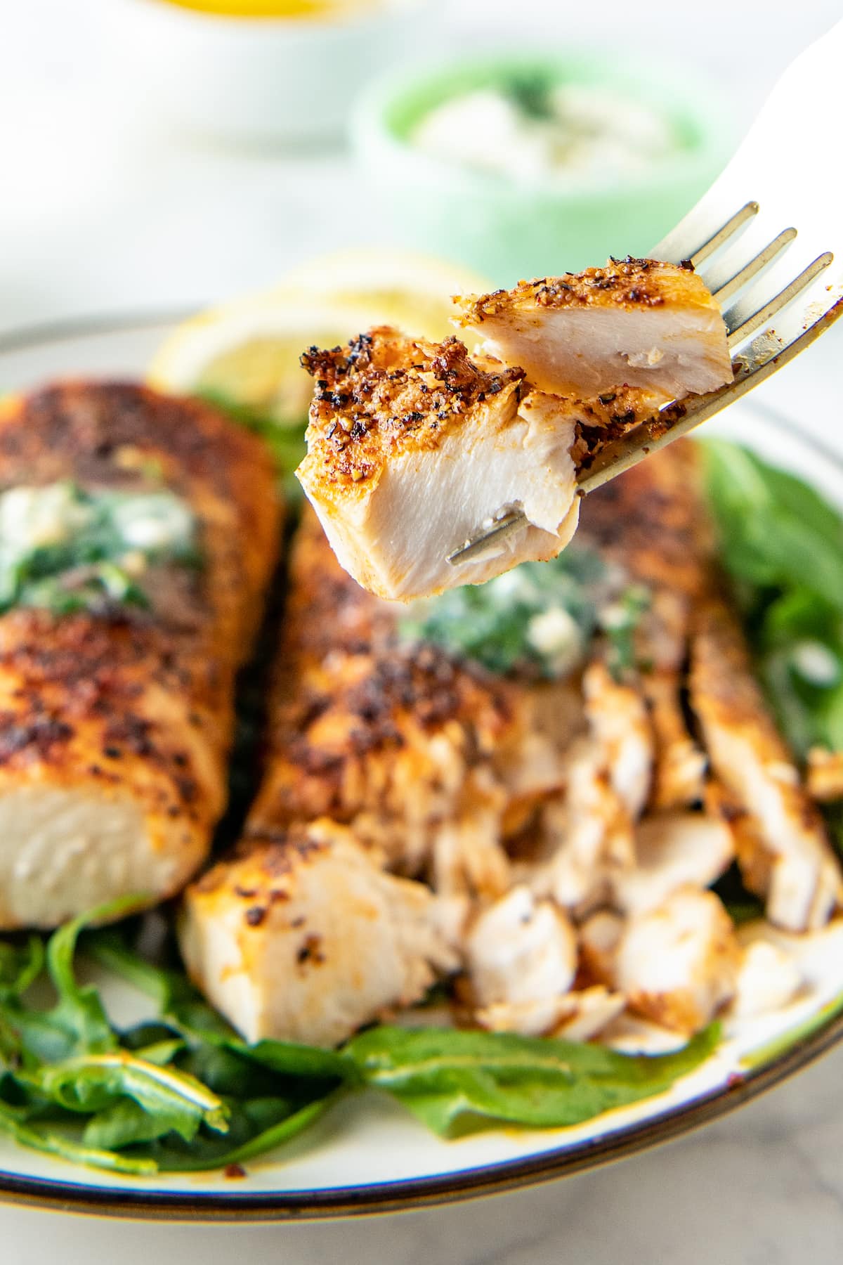 A fork is piercing a bite sized portion of boldly seasoned mahi mahi. 