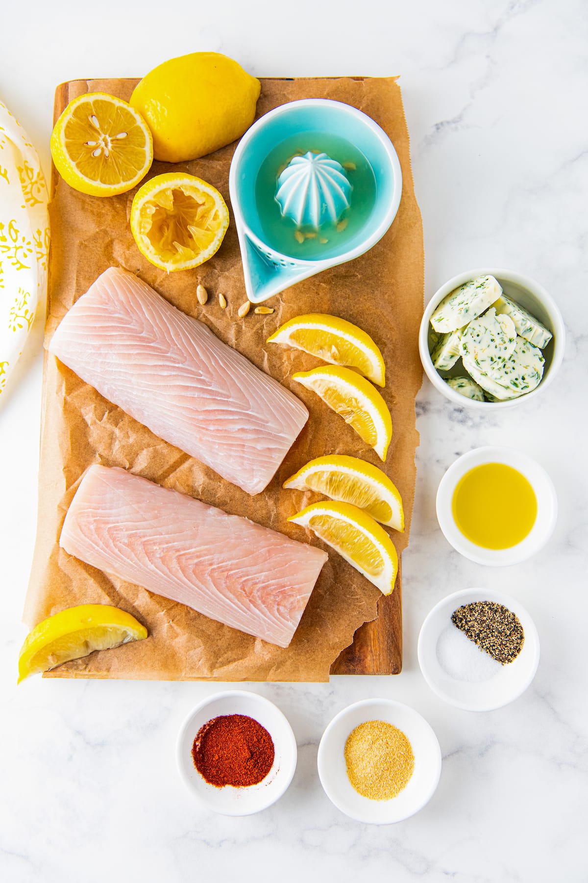 a display of ingredients including mahi mahi, oil, salt and pepper, herb butter, and lemons