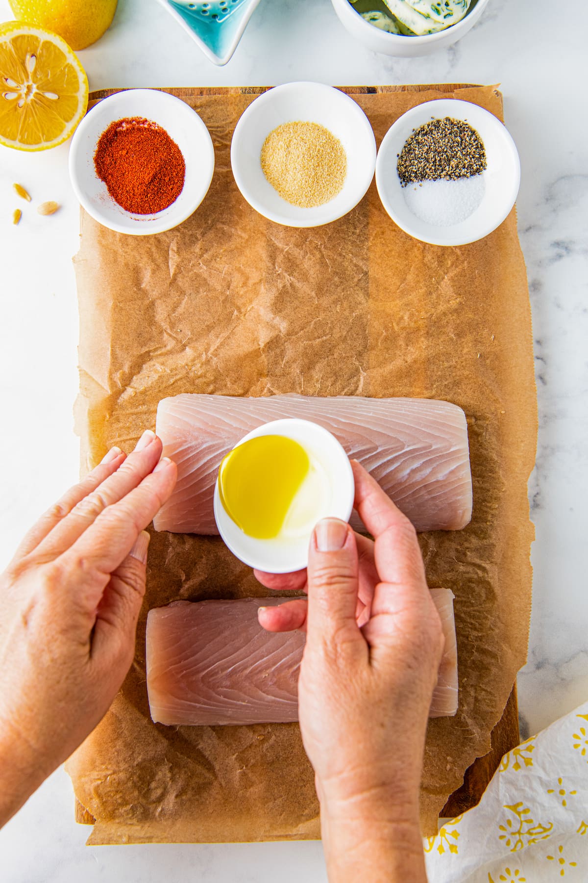 Olive oil is being drizzled on top of uncooked fish. 