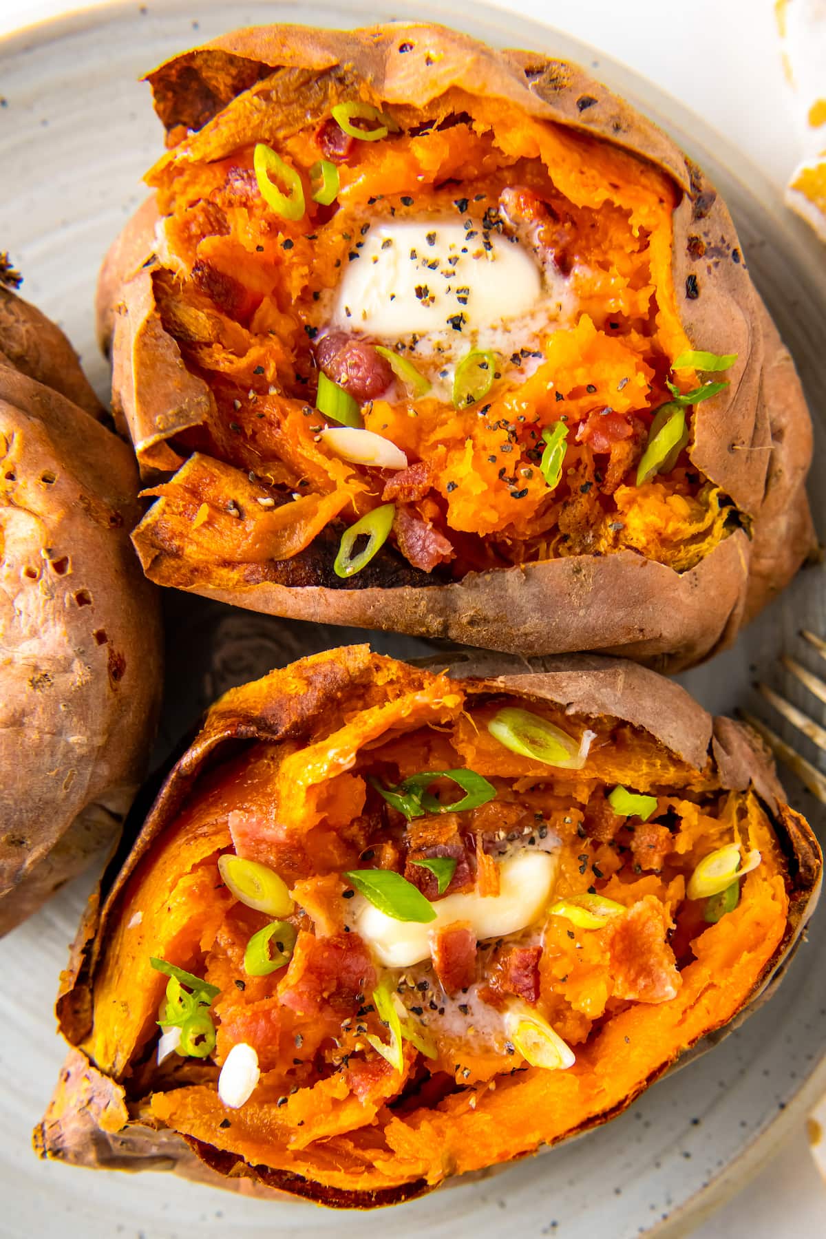 whole baked sweet potatoes with butter and herb garnish