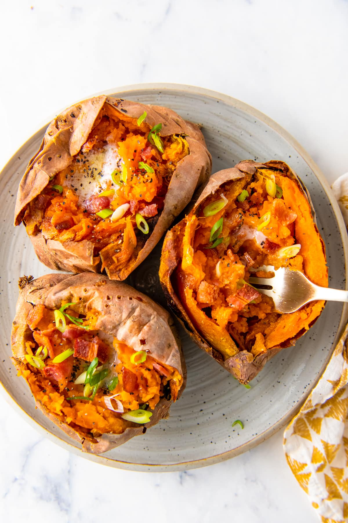 three whole air fryer sweet potatoes with butter and green onions