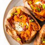 whole baked sweet potatoes with butter and herb garnish