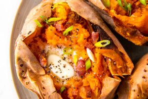 whole baked sweet potatoes with butter and herb garnish