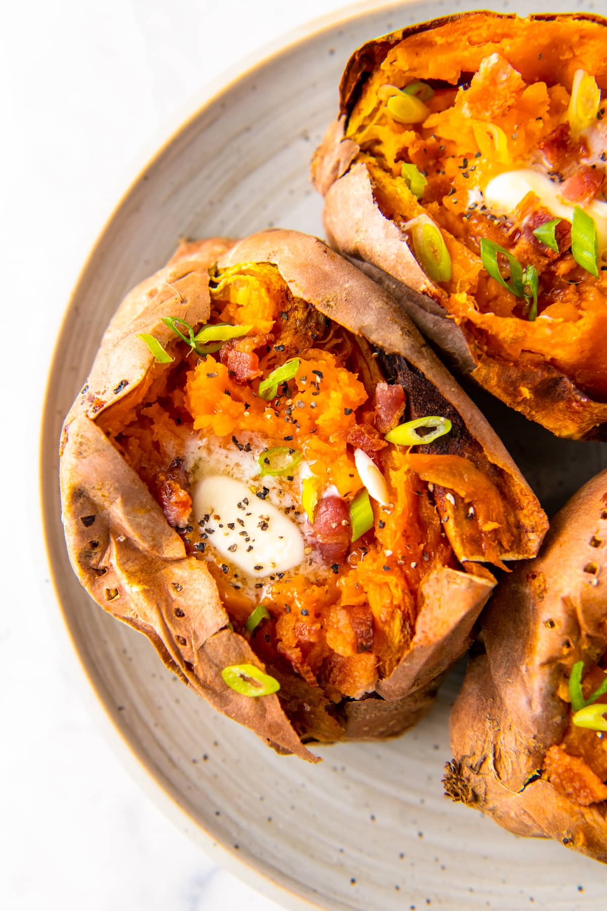 whole baked sweet potatoes with butter and herb garnish