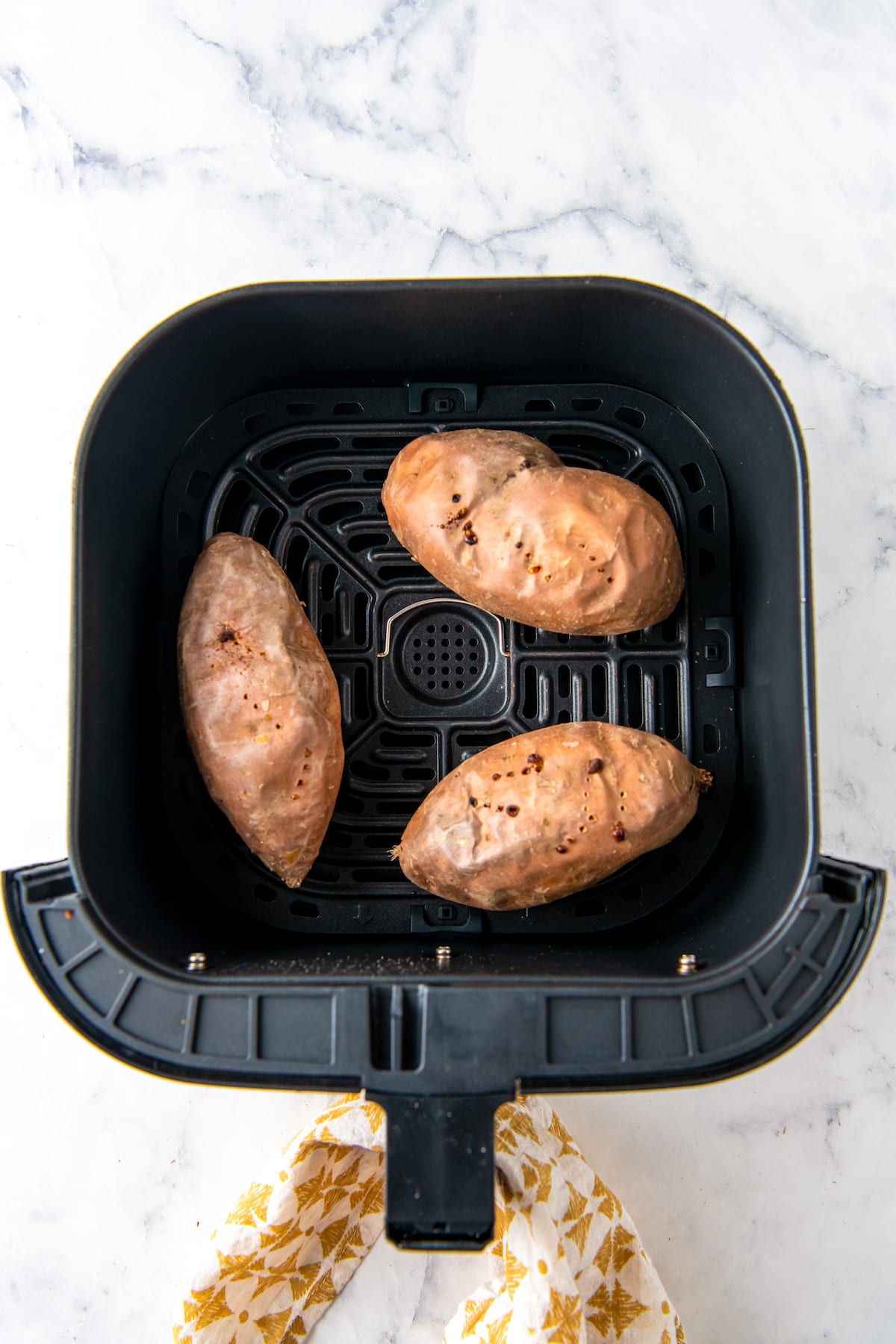 three whole sweet potatoes in an air fryer that have been cooked