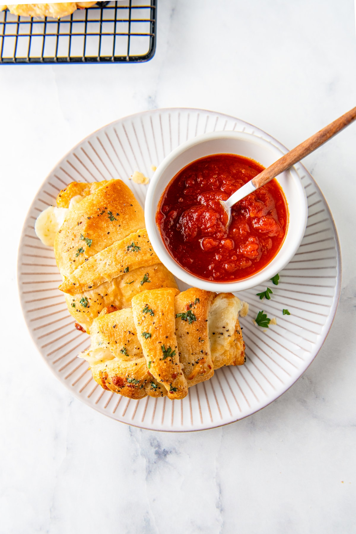 a plate with crescent roll and bowl of tomato sauce