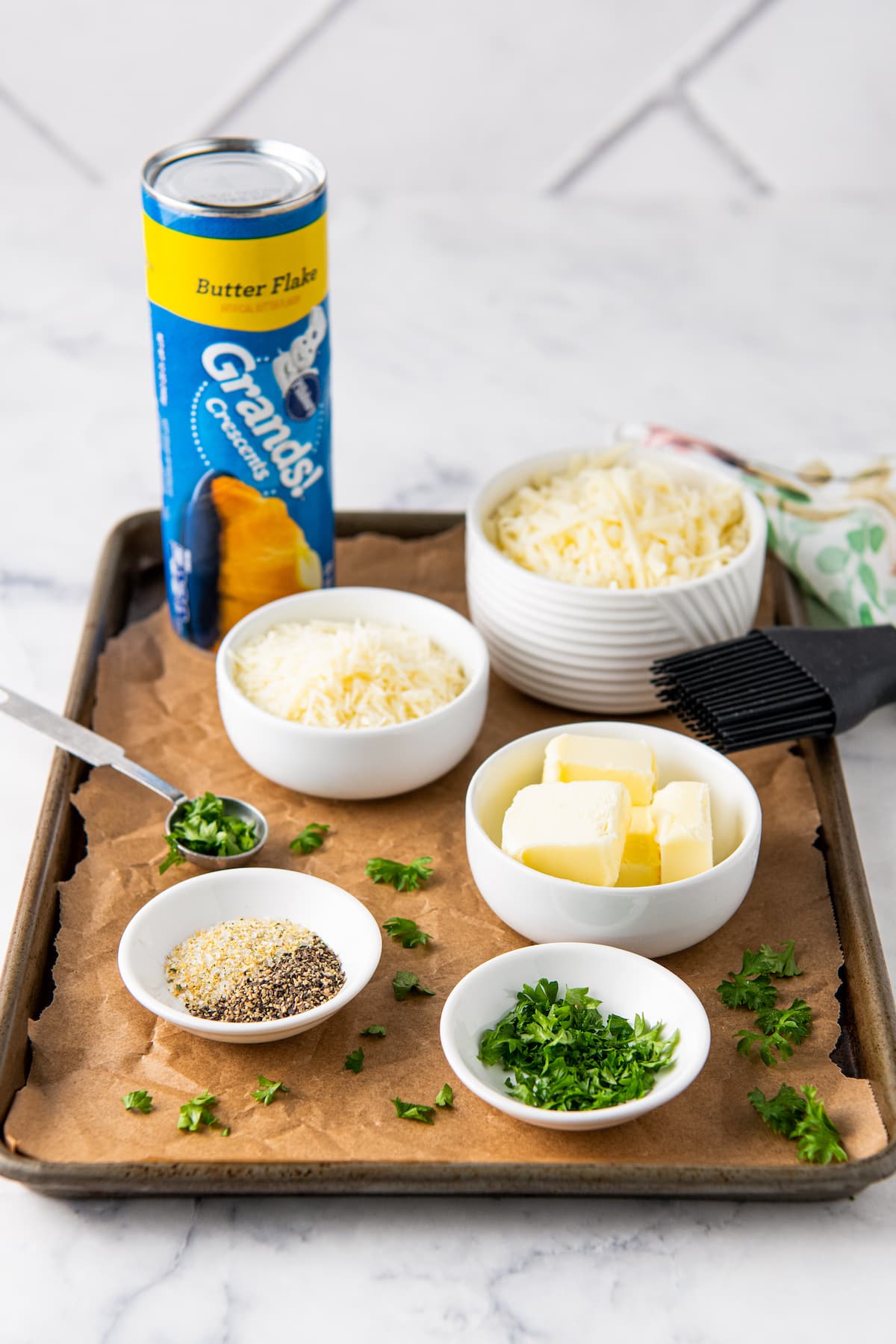 cooking ingredients on a sheet tray like canned dough, seasonings, butter and cheese