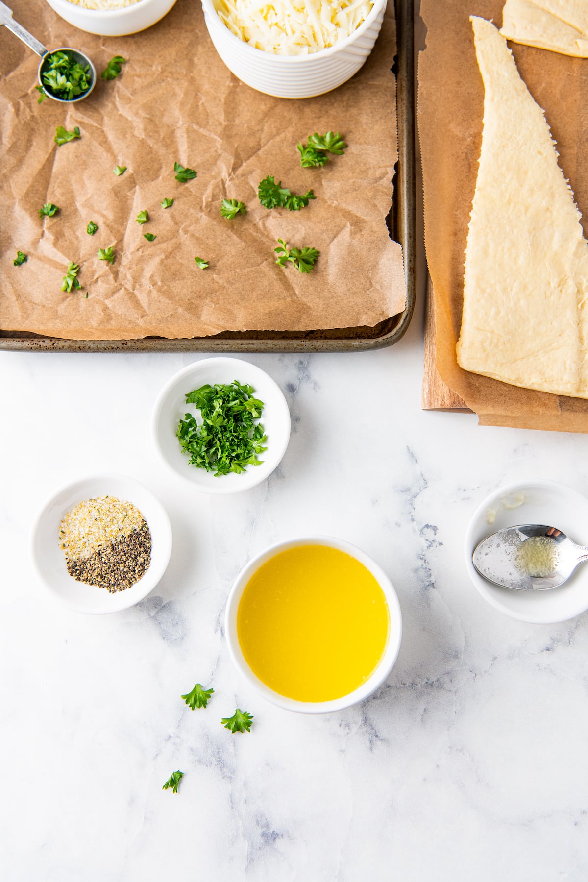 top view of kitchen counter with small bowls of seasonings and butter, plus crescent dough