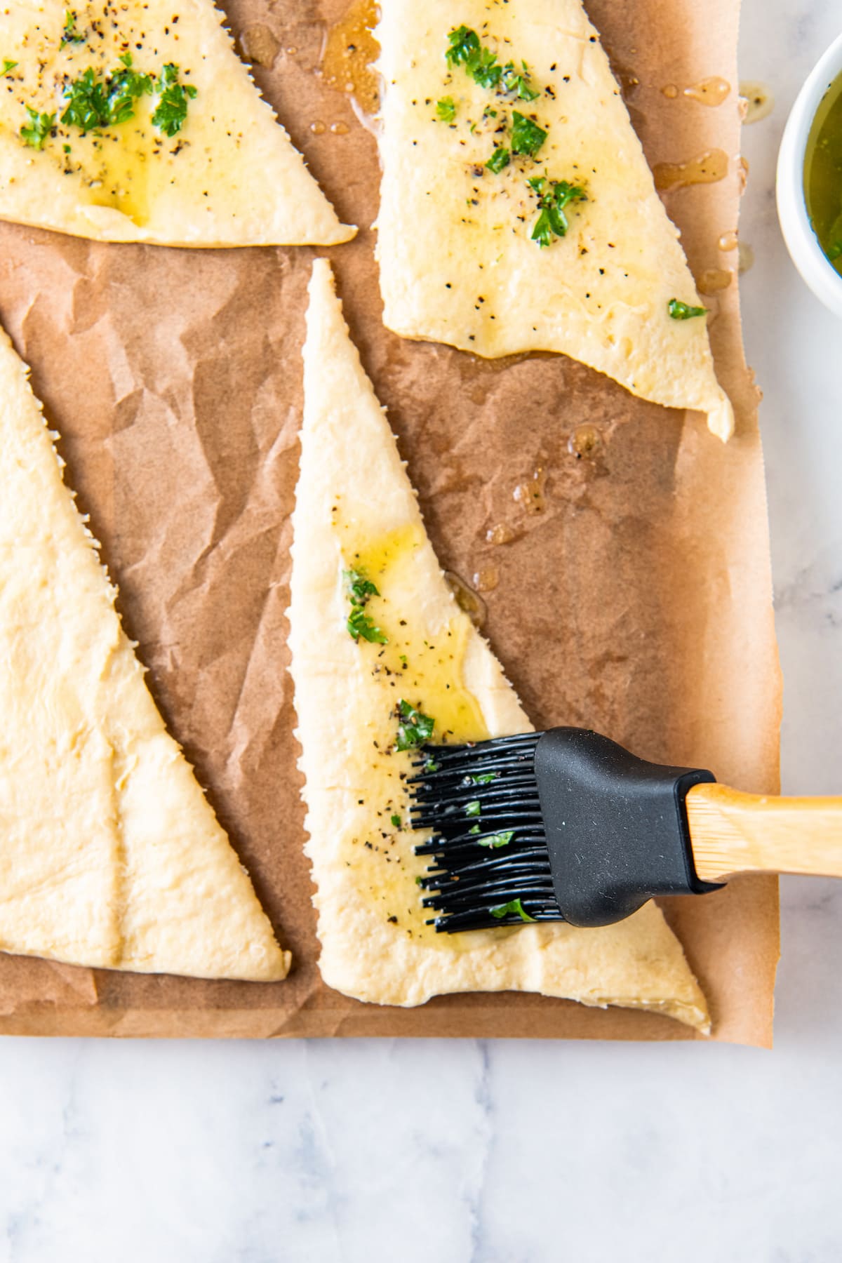 brushing herb melted butter on crecsent rolls