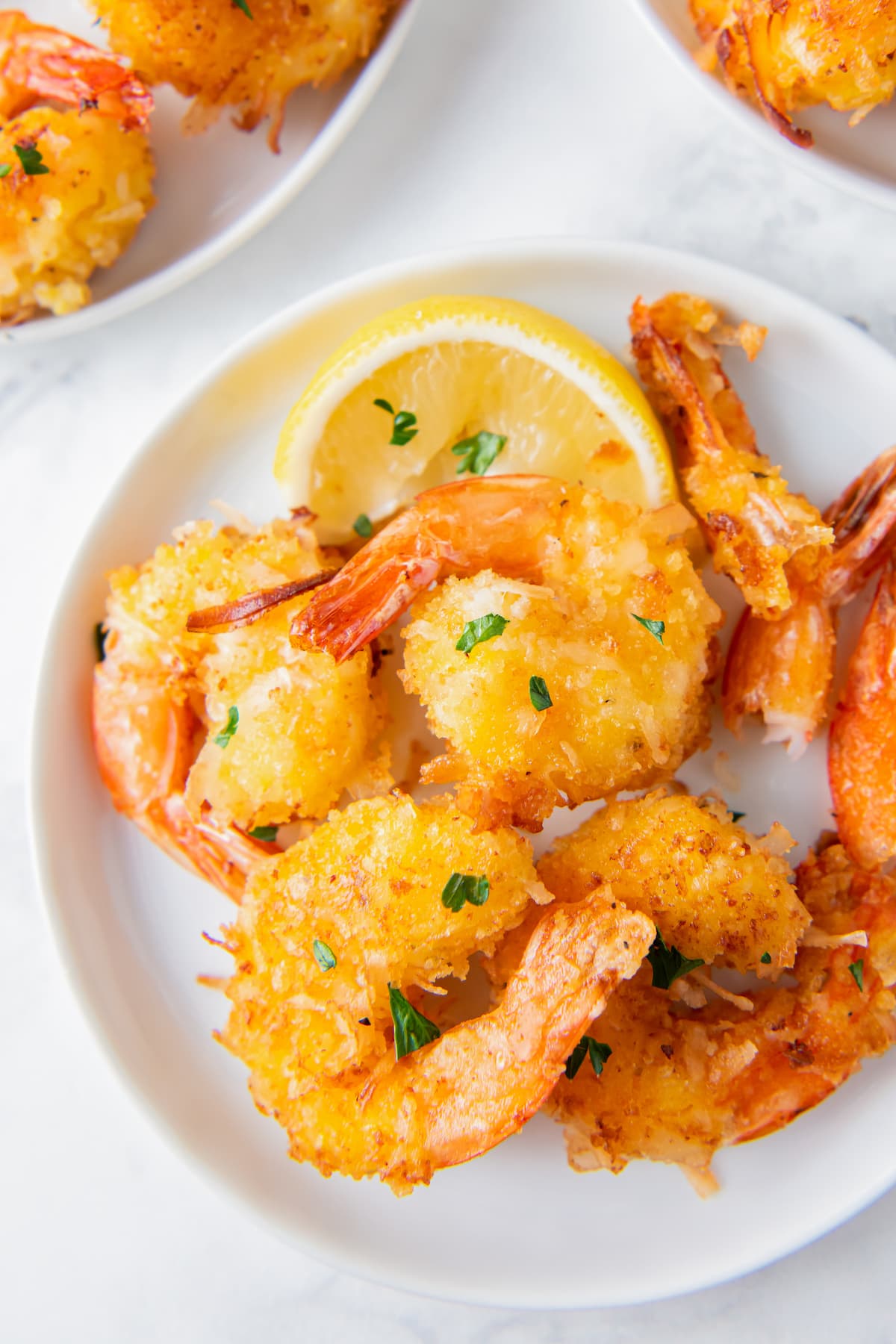 a plate of coconut shrimp with a lemon wedge