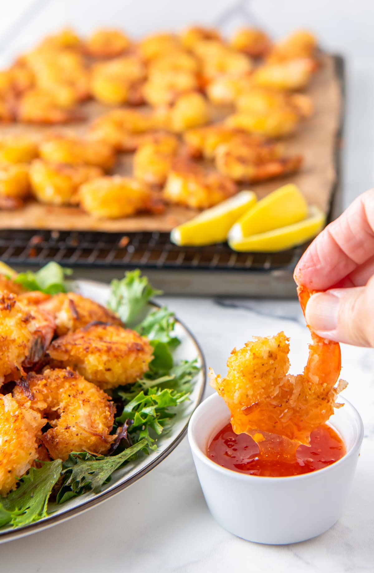 dipping coconut shrimp into a tangy red sauce