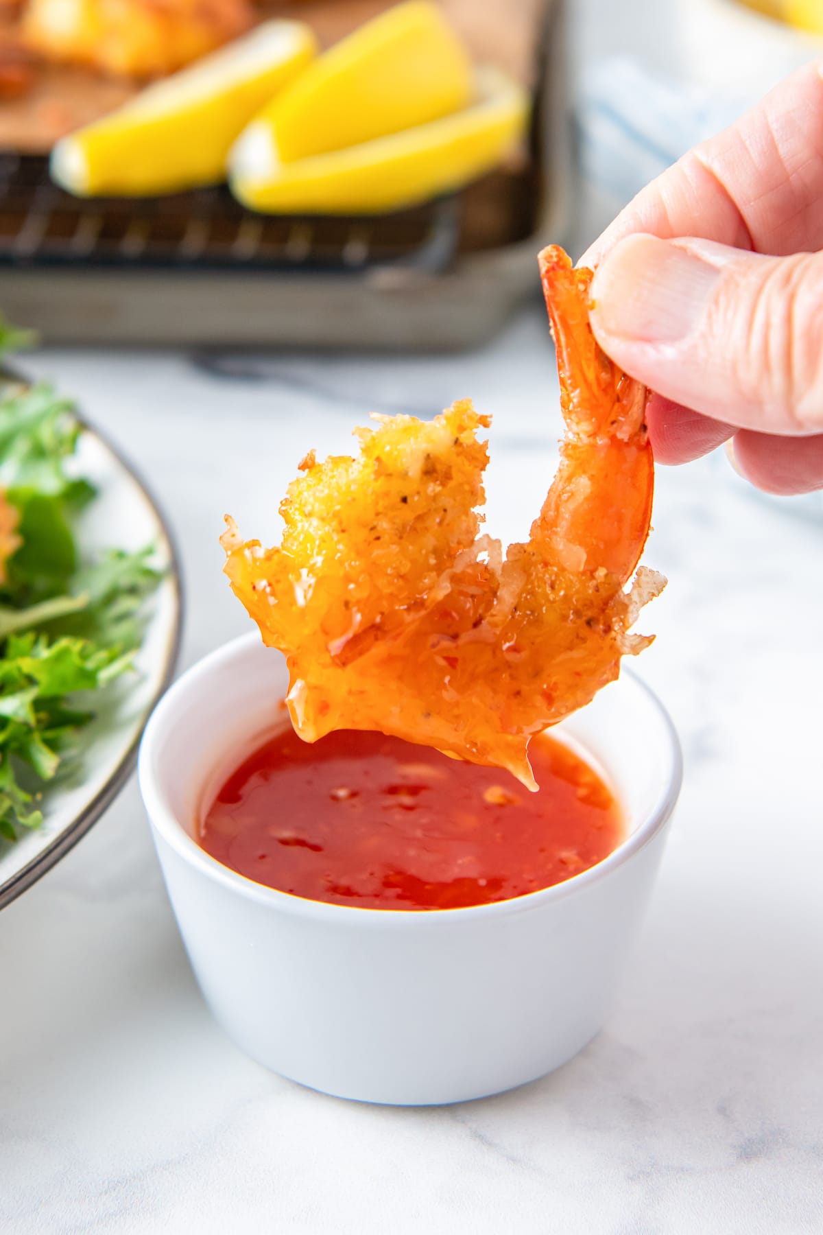 dipping coconut shrimp into a tangy red sauce