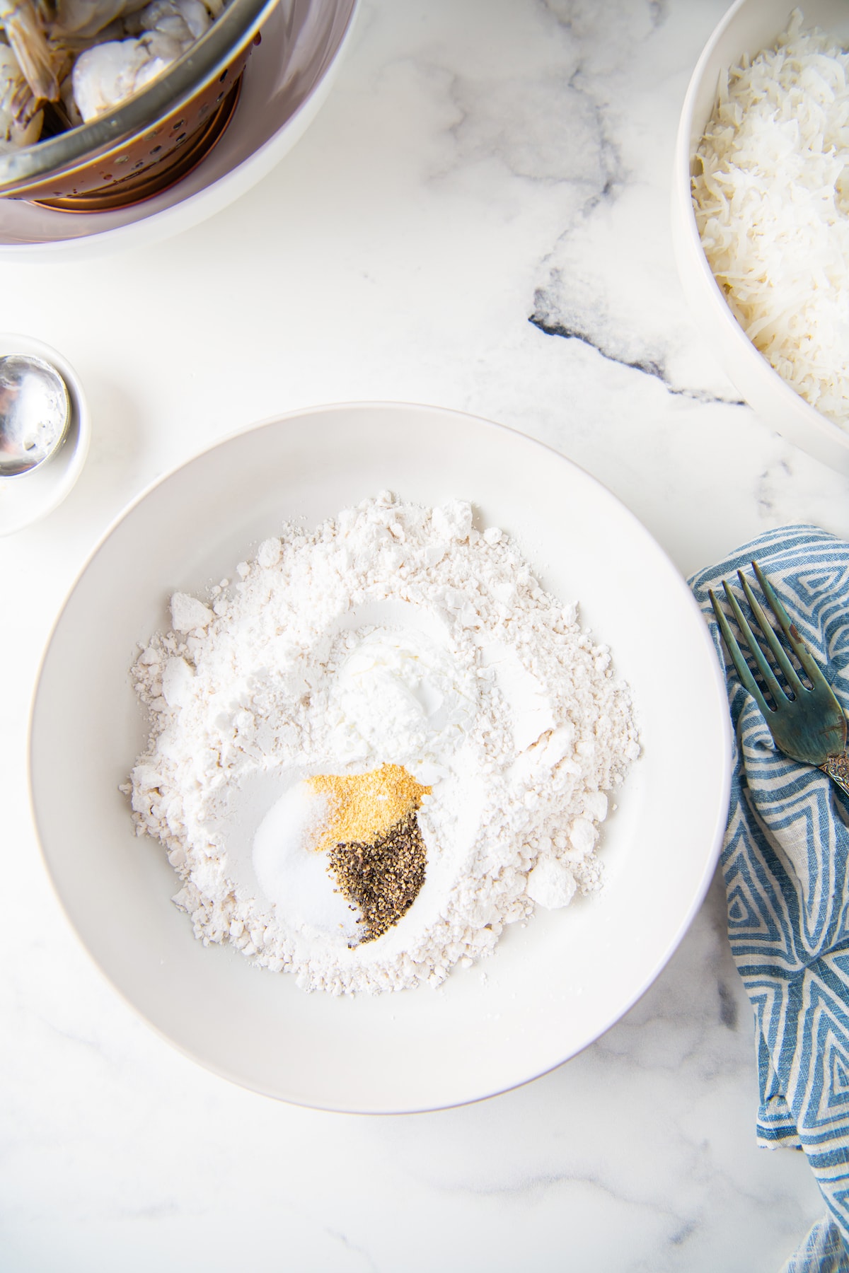 a bowl with flour, salt, pepper, and garlic powder