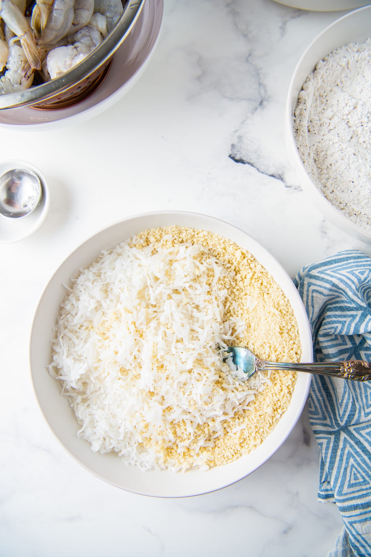 tossing dried coconut into a flour mixture in a bowl