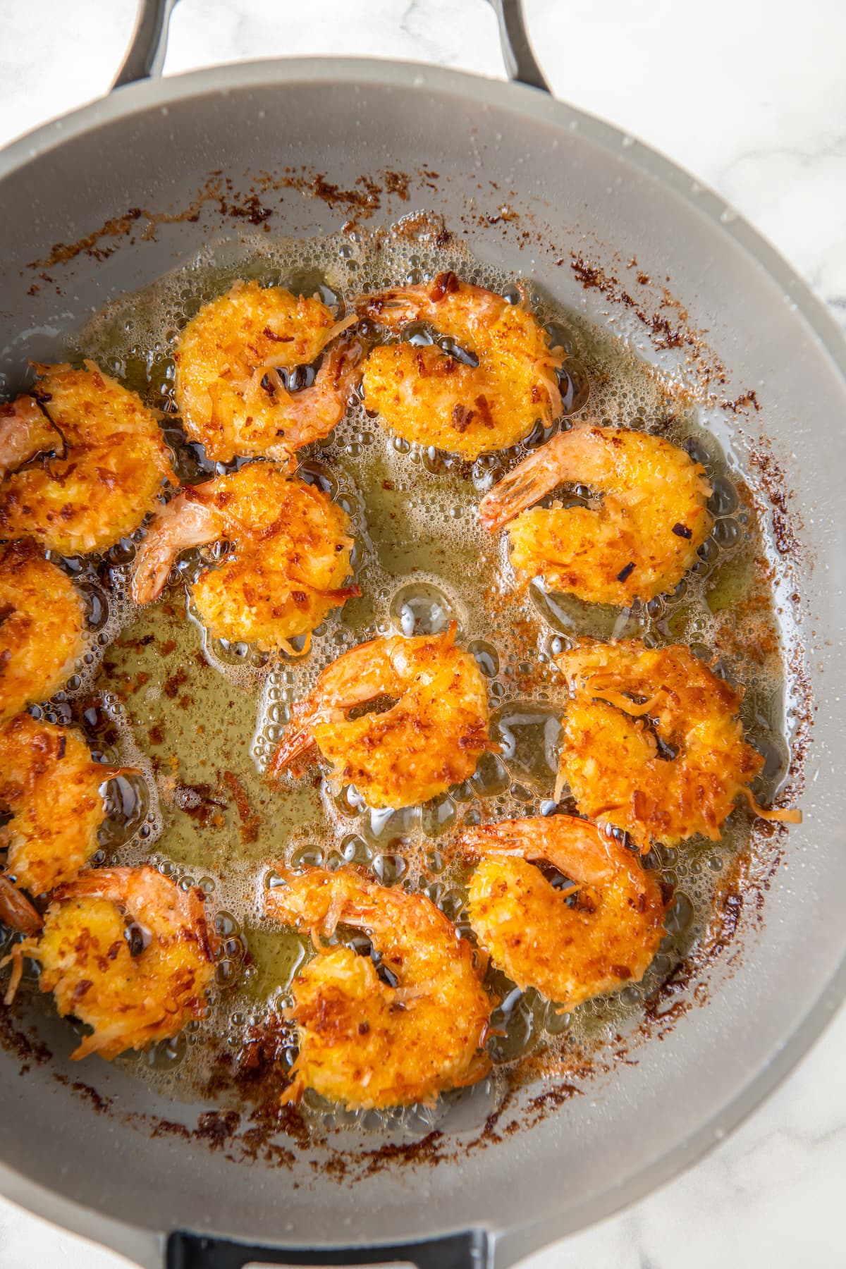 frying coconut shrimp in a pan