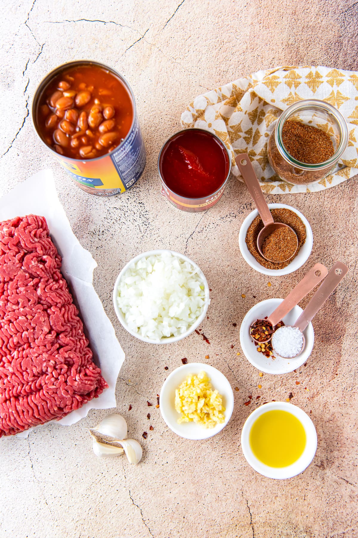 ingredients to make easy chili like ground beef, seasonings, onions, beans, and garlic