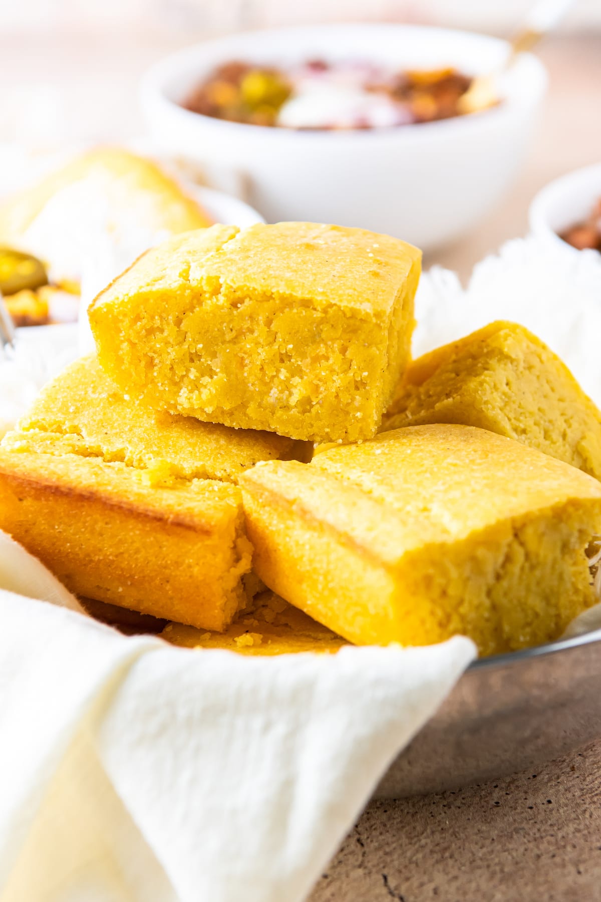 cut on pieces of cornbread in a bowl lined with a towel