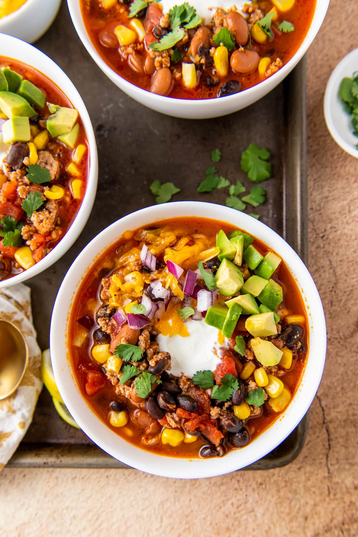 a bowl of easy taco soup with sour cream, avoacdo, and cilantro garnish