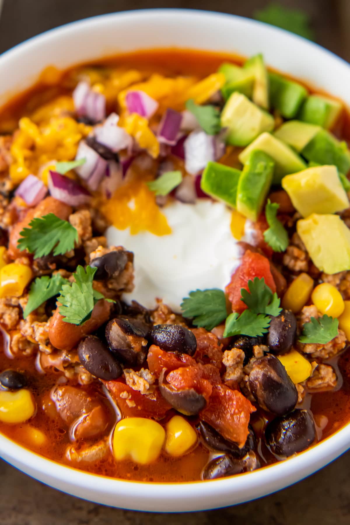 a bowl of easy taco soup with sour cream, avoacdo, and cilantro garnish