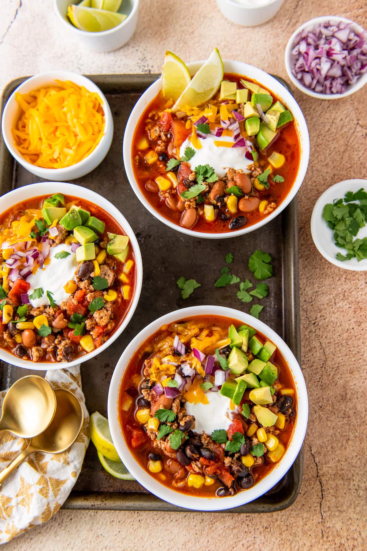 three bowls of taco soup with cilantro, sour cream, and avocado garnish