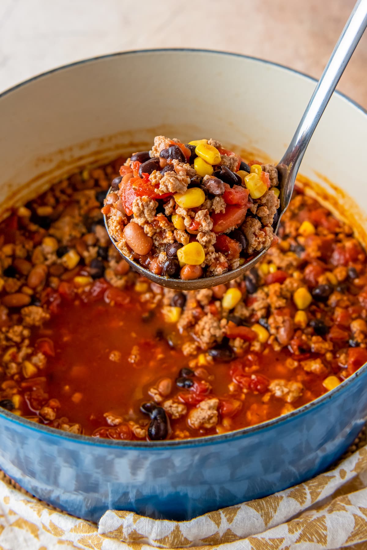 a ladle of taco soup including beans, tomatoes, and ground beef in a tomato broth