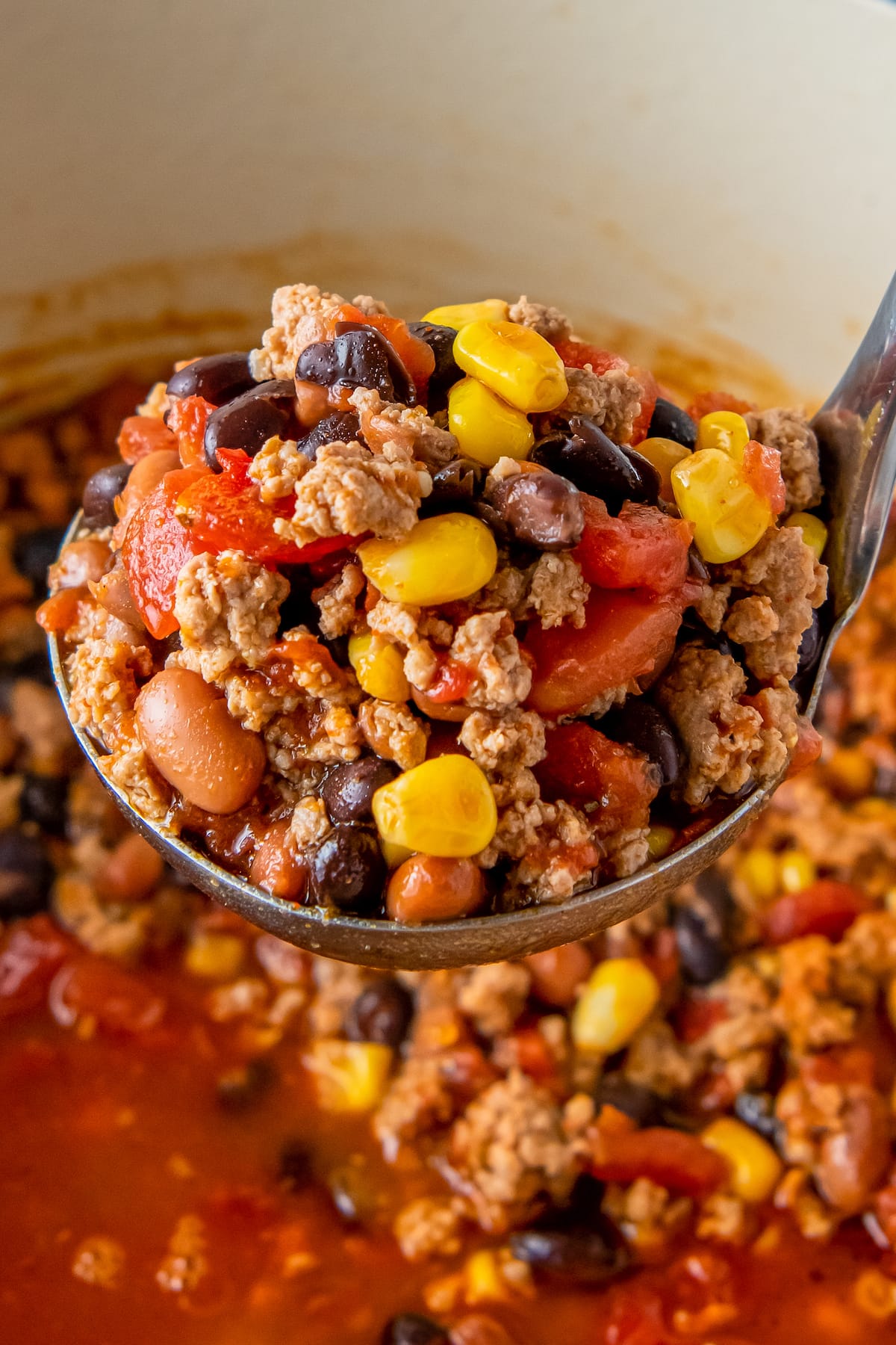 a ladle of taco soup including beans, tomatoes, and ground beef in a tomato broth