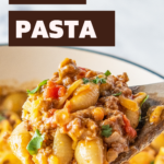 A wooden spoon scooping up a serving of taco pasta.