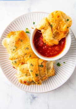 a plate with crescent roll and bowl of tomato sauce