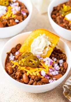 a big bowl of chili with a piece of cornbread in it