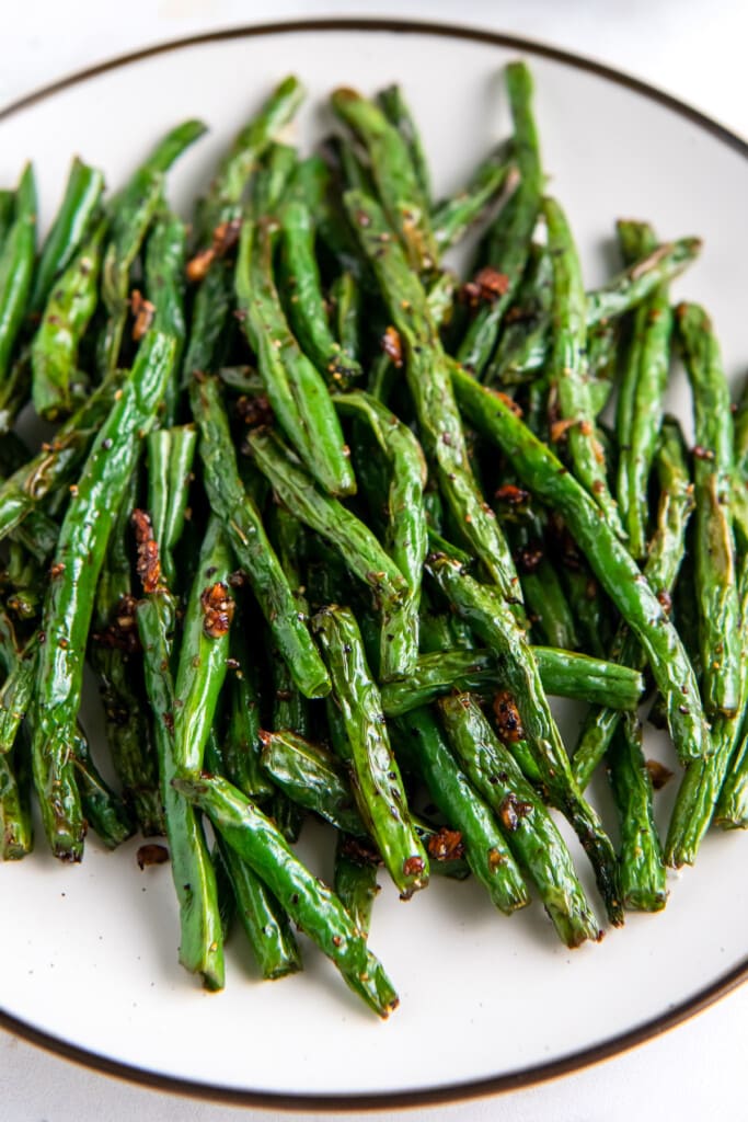 close up of air fryer green beans on a white plate.