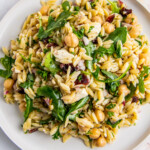 a plate of a salad made with orzo, arugula, red onion, garbanzo beans, and feta