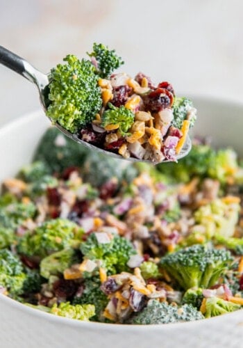 a bowl of broccoli salad with a fork taking a bite out of it
