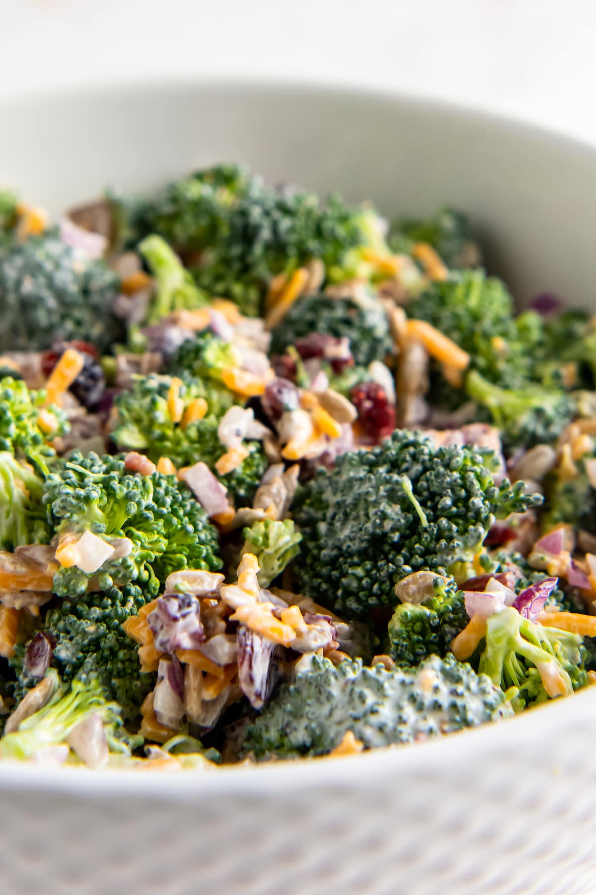 close up of broccoli and bacon salad with creamy dressing and shredded cheese