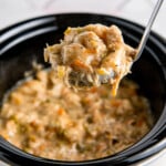 a ladle of chicken and dumplings over a crockpot