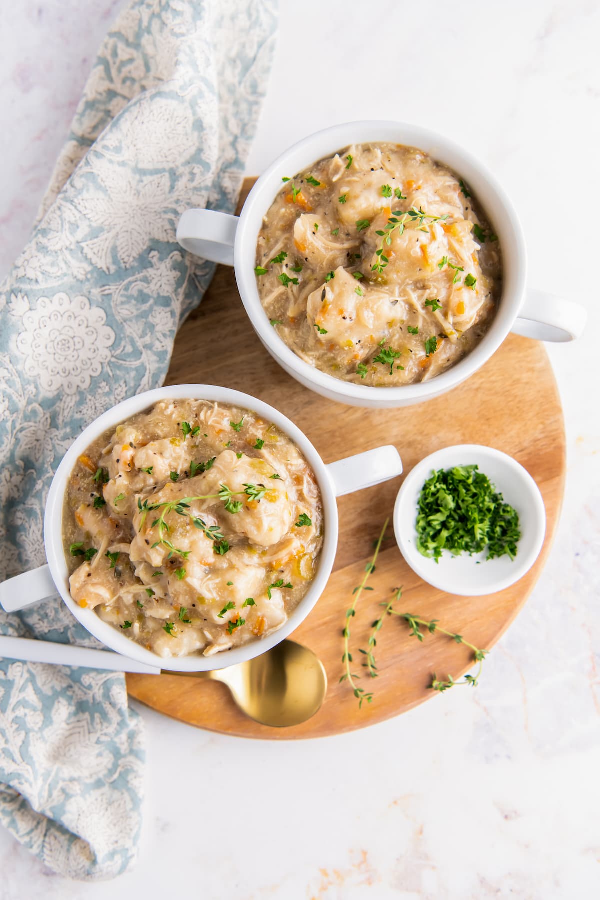 two servings of chicken and dumplings in small white crocks