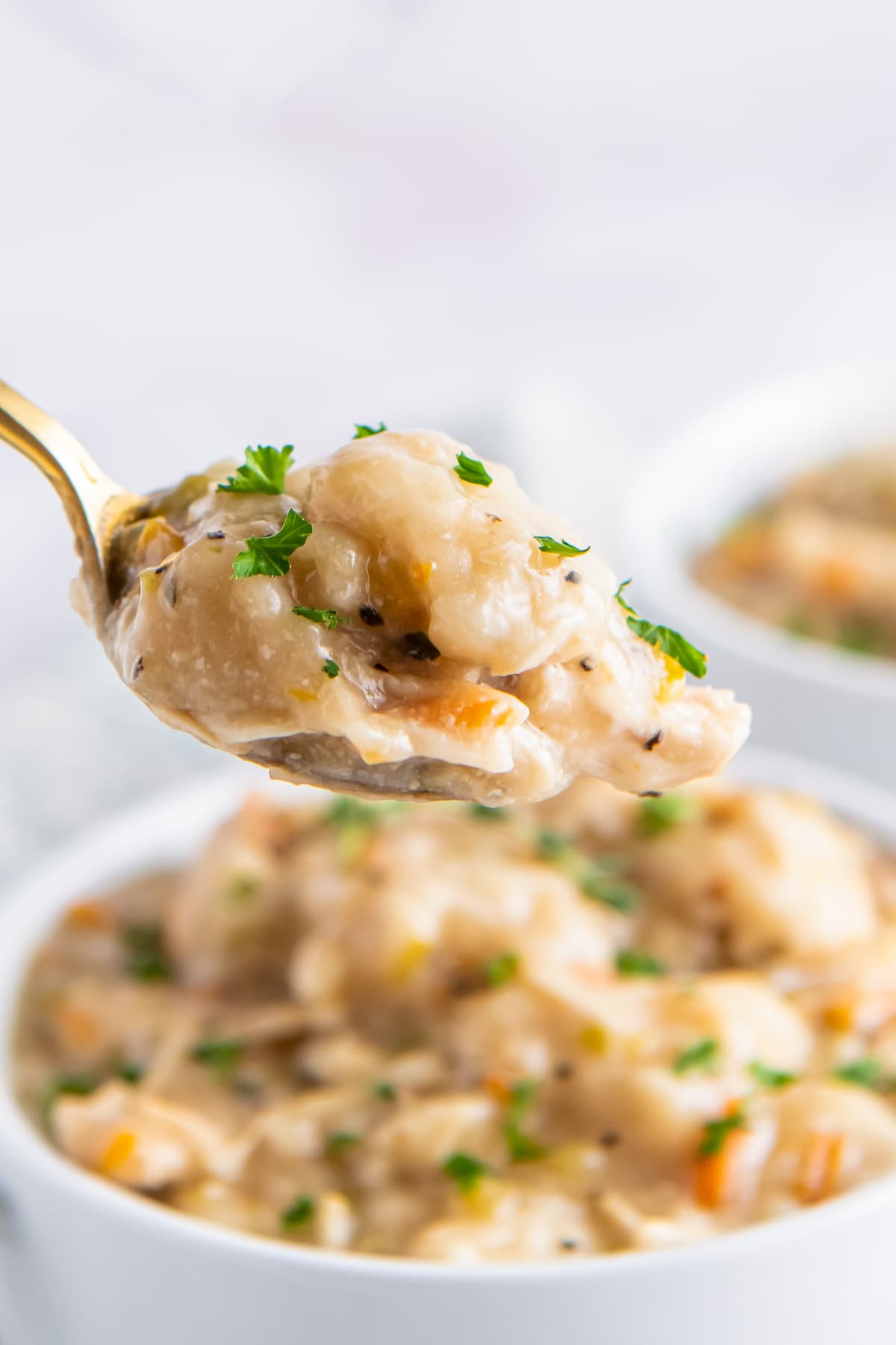 a spoonful of a creamy chicken dish with fresh herbs