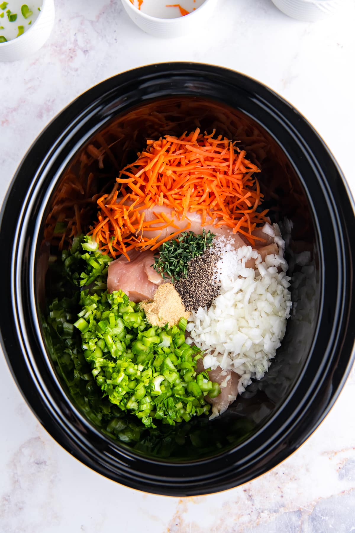 a crockpot filled with diced celery, carrots, onions, and seasonings