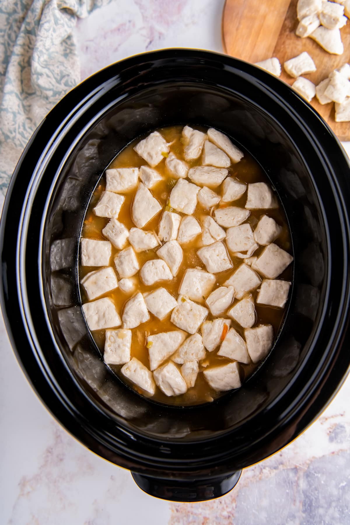 diced biscuit dough pieces in a crockpot with broth