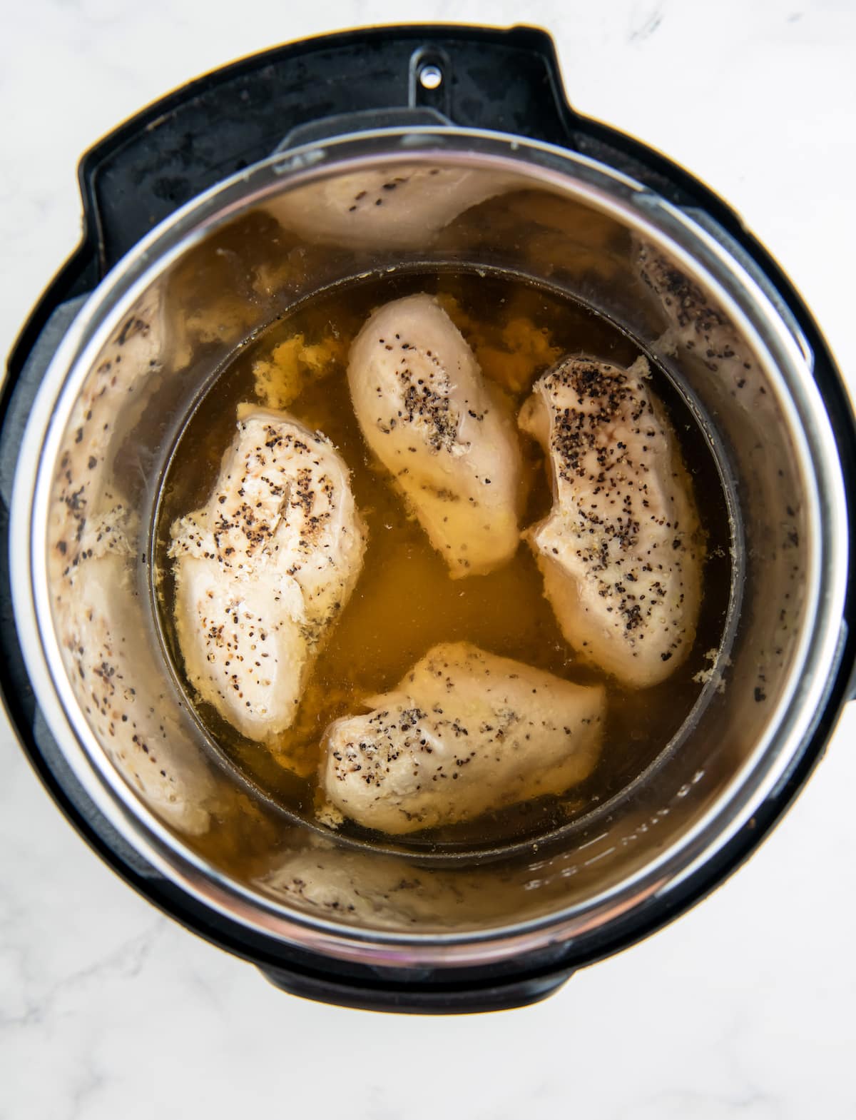 four chicken breasts in broth in an instant pot