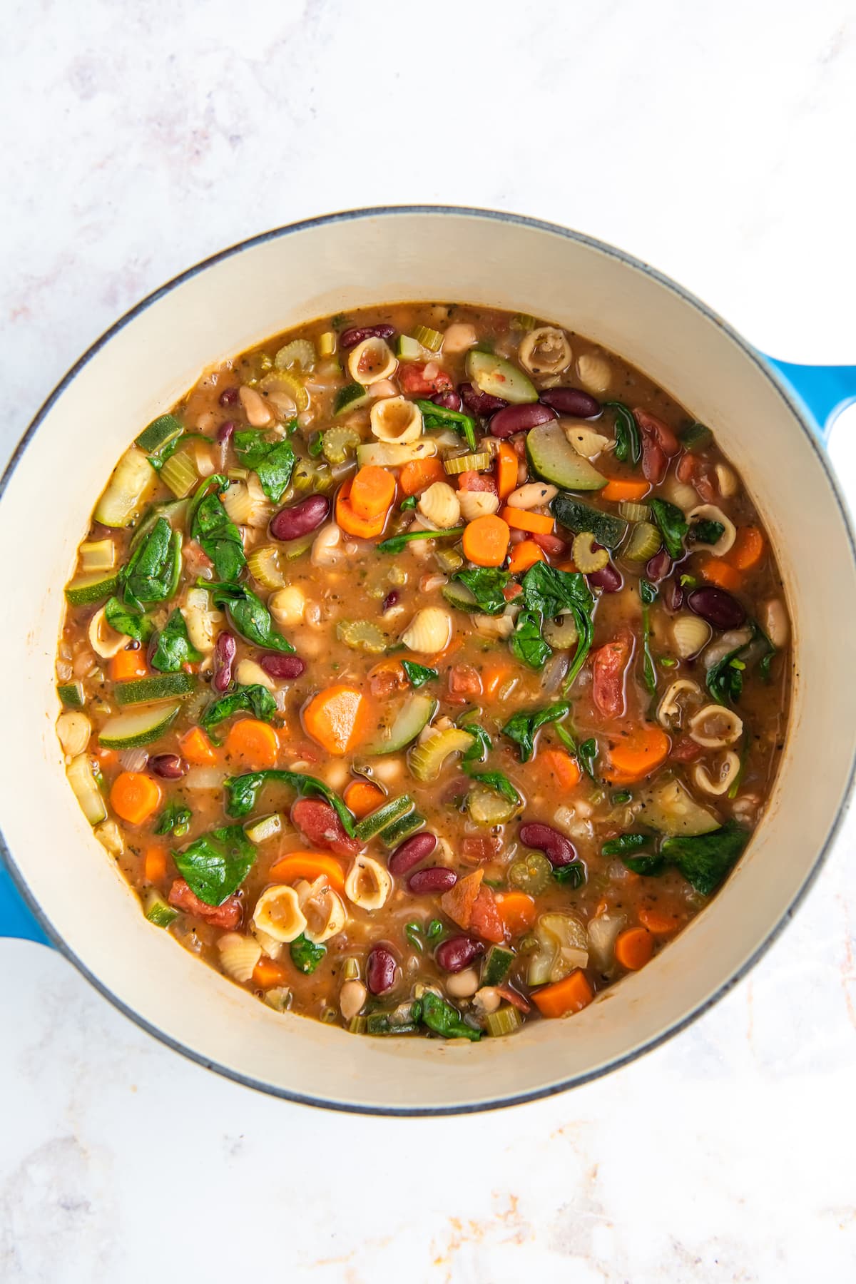 a large pot with minestrone soup with tomato broth, noodles, beans, and vegetables