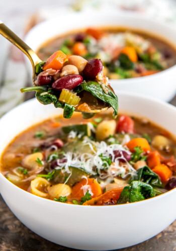 a bowl of minestrone soup with a rich tomato broth, vegetables, noodles, and cheese