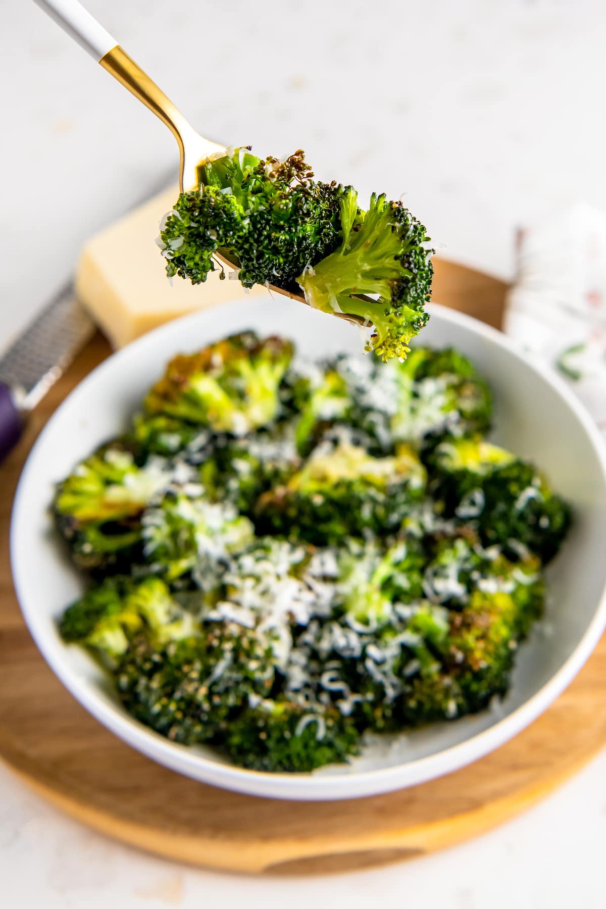 a bowl of cooked broccoli with sprinkled parmesan cheese