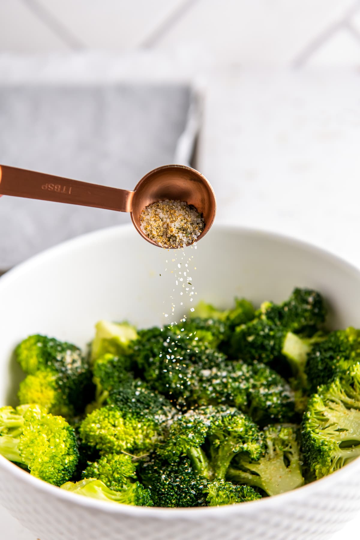 seasoning a bowl of broccoli