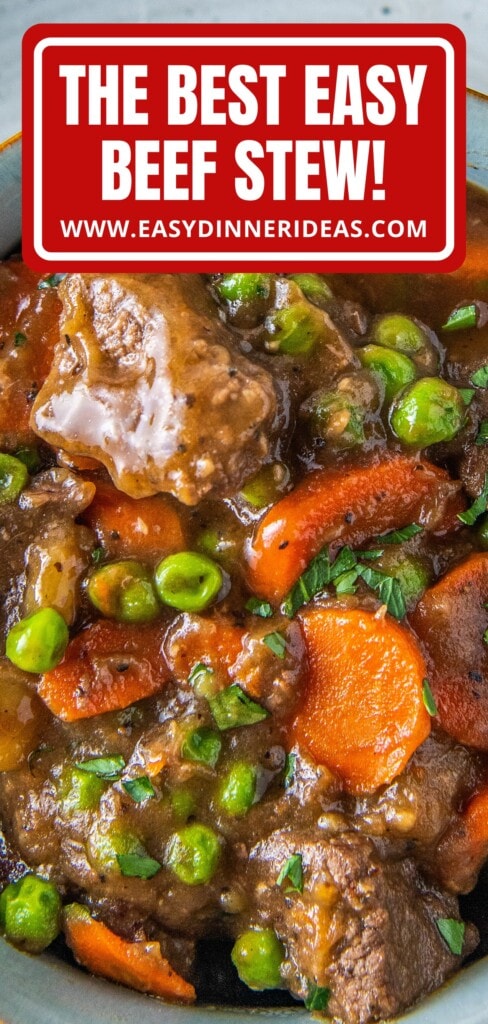 Stovetop beef stew with carrots and peas in a bowl with fresh herbs on top.