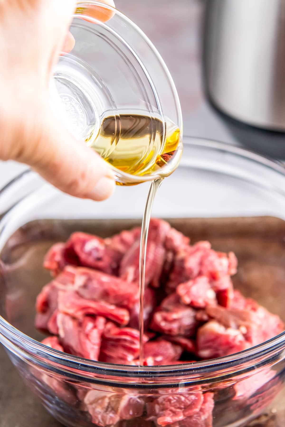 pouring oil over a bowl of beef pieces