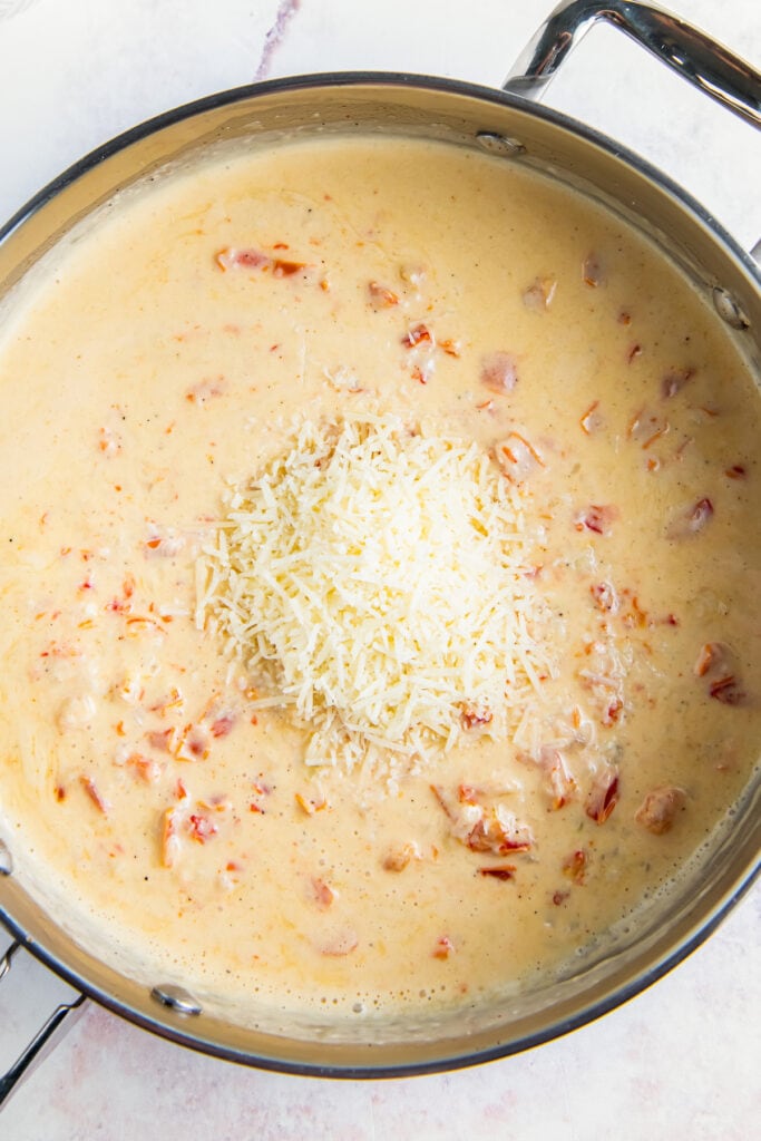 Stirring in cheese to cajun shrimp pasta.