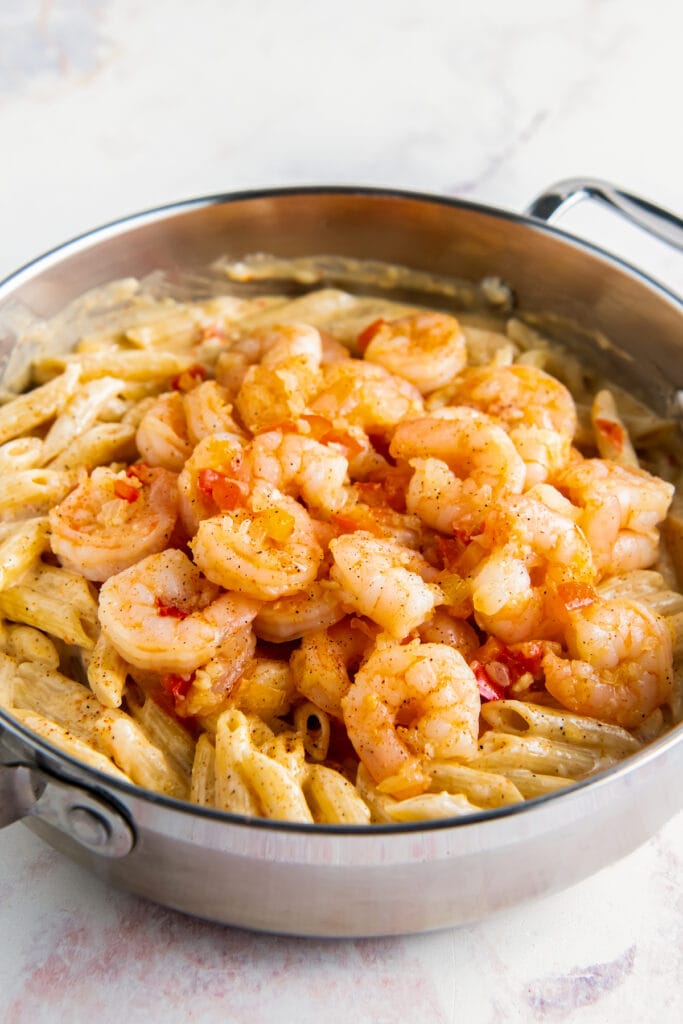 Adding cooked shrimp to pasta.