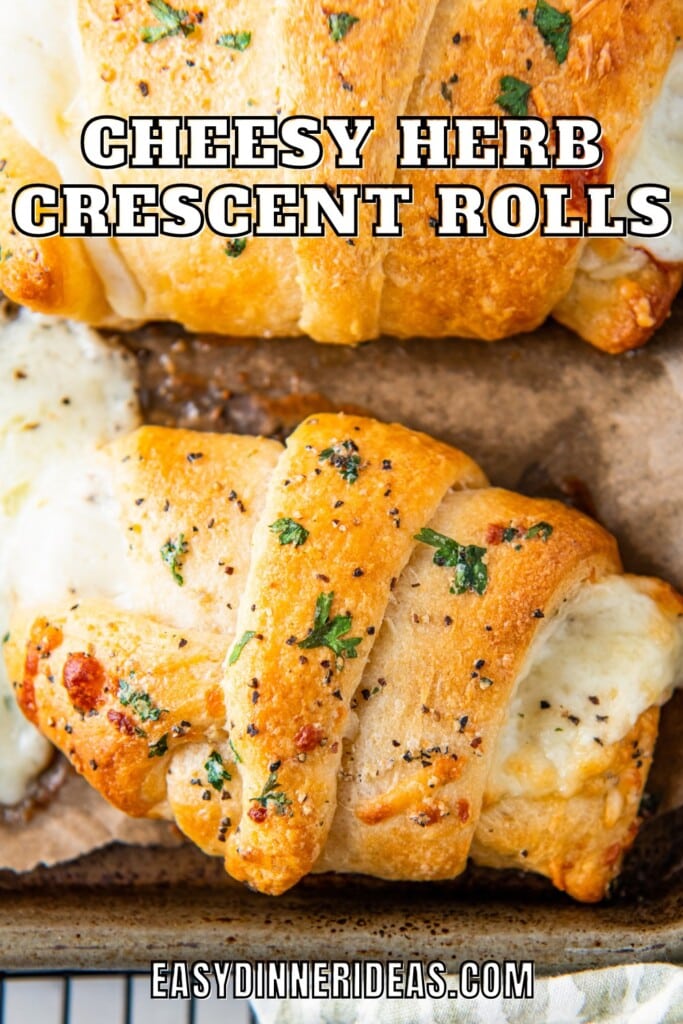 Cheesy herb crescent rolls on a baking sheet.