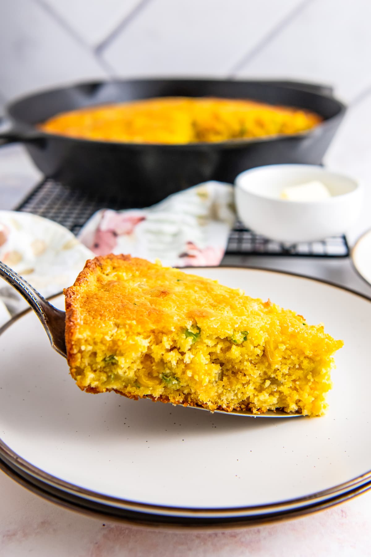 a slice of cheesy cornbread being placed on a plate